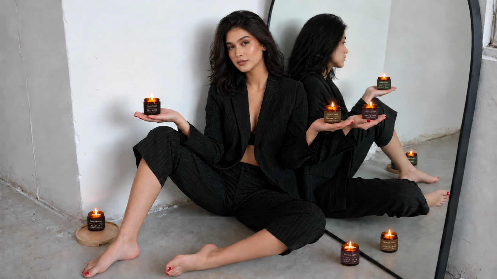 Enaya seated in front of a mirror with the four small House of Enaya candles in their updated labels